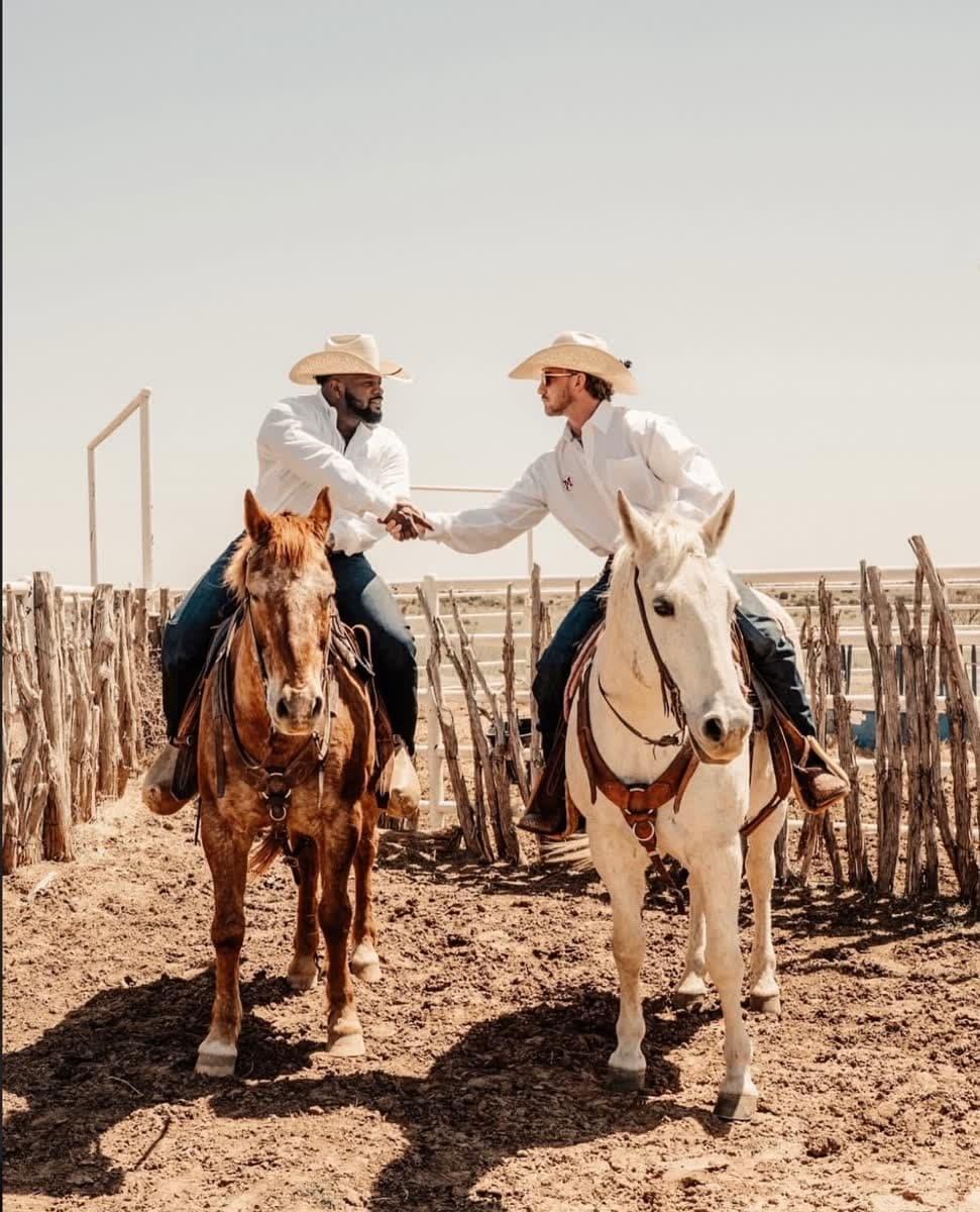 Two cowboys shaking hands on horseback